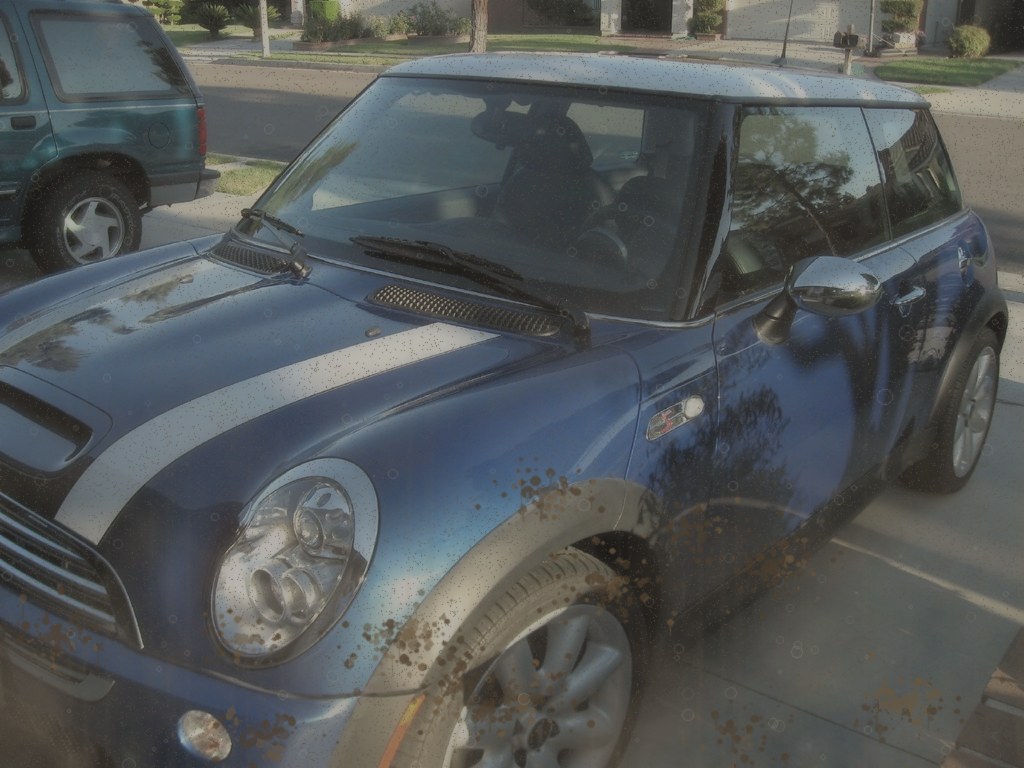 Dusty dull blue hatchback with road grime before a hand wash